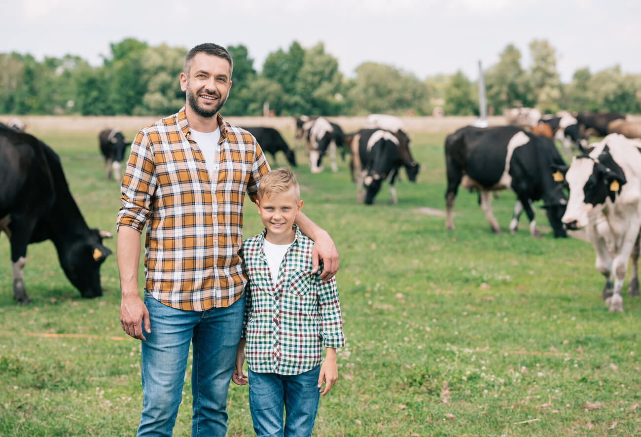 Lanwirt steht stolz mit seinem Sohn auf der Rinderweide
